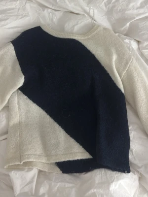 Stickad tröja med svartvit diagonal - Snygg stickad tröja med ett unikt diagonalt mönster i svart och vitt. Tröjan har rund halsringning och långa ärmar. Perfekt för dig som gillar en stilren men ändå iögonfallande look. Storlek 146/152 men passar xxs också