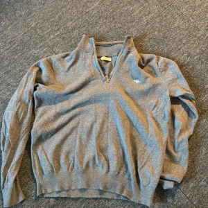 Grå half zip tröja från GANT - Snygg grå långärmad tröja från GANT med half zip och liten broderad logga på bröstet. Tröjan är i mjuk bomull och har ribbade muddar vid ärmslut och nederkant. Perfekt för lager-på-lager och chill dagar. Ord pris typ 1099 knappt använt den 