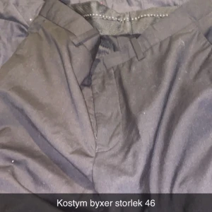 Svarta kostymbyxor stl 46 - Snygga svarta kostymbyxor i klassisk modell med hällor för bälte och diskret dragkedja. Perfekta för en dressad look och passar till skjorta eller kavaj. Byxorna har rak passform och är tillverkade i ett mjukt tyg som känns bekvämt hela dagen.
