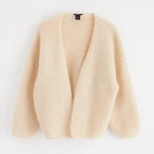 Beige stickad kofta från Lindex - Mysig och fluffig beige stickad kofta från Lindex i oversized modell. Koftan har djup v-ringning, lång ärm och är perfekt att slänga på sig för en chill look. Superenkel att matcha med allt och ger en soft vibe.