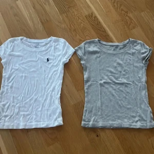 2-pack t-shirts från Ralph Lauren - Två klassiska t-shirts från Ralph Lauren i storlek S. En vit med liten broderad logga på bröstet och en ljusgrå utan logga. Båda har rund halsringning och korta ärmar. Perfekta basplagg i mjuk bomull för en clean och enkel stil.
