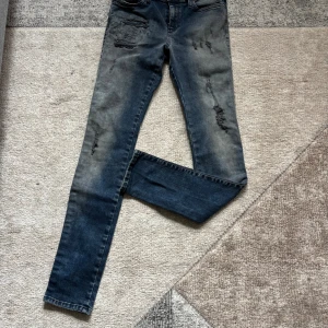 Diesel Skinzee skinny jeans blå W29 L32 - Snygga blå Diesel Skinzee jeans med skinny fit och slitna detaljer framtill. Jeansen har en klassisk femficksdesign, stretchigt material och normal midja. Färgen är tvättad blå med ljusare partier och coola slitningar för en trendig look.