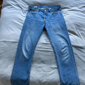 Levi's 501 ljusblå jeans straight fit - Säljer ett par klassiska Levi's 501 jeans i ljusblå tvätt. De har rak passform, normal midja och fem fickor. Jeansen är i 100% bomull och har den ikoniska läderpatchen bak. Perfekta för en avslappnad och tidlös stil.