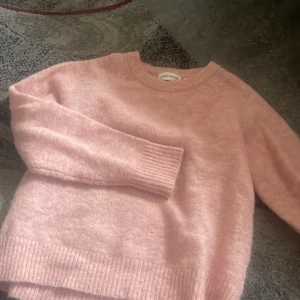 Rosa stickad tröja Carin Wester XS - Supermjuk och fluffig rosa stickad tröja från Carin Wester i storlek XS. Tröjan har rund halsringning, långa ärmar och breda ribbade muddar vid ärmslut och nederkant. Perfekt för lager-på-lager och en chill look.