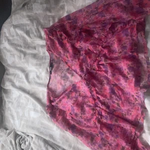 Blommig rosa söt topp från BikBok - Supersöt blommig topp från BikBok i storlek L men är som M i storlek. Den har ett blommigt mönster i rosa, lila och röda toner, v-ringning och volangdetaljer framtill. Toppen är gjord i ett lätt och transparent syntetmaterial och har långa ärmar. Kommit till användning, är i bra skick😊