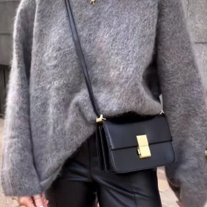 Grå fluffig stickad tröja - Supermjuk och oversized grå stickad tröja med lång ärm och rund hals. Tröjan har en fluffig yta och avslappnad passform, perfekt att slänga på sig när det är kallt ute. Enkel att styla med jeans eller skinnbyxor för en chill look.