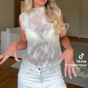 Vit spets topp från Gina Tricot - Superfin transparent blus från Gina Tricot i vit spets med blommiga detaljer. Ärmlös modell med hög hals och vågiga kanter. Endast testad men saknar prislappen!