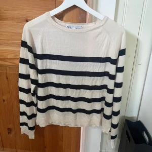 Randig beige och svart tröja från Zara - Snygg beige tröja från Zara med svarta horisontella ränder. Tröjan har rund halsringning och långa ärmar. Perfekt för lager-på-lager och passar till både jeans och kjol. Tunn och mjuk i materialet. 