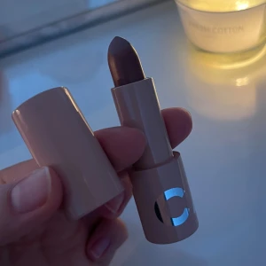 CAIA Splendour Series Chic läppstift - Snyggt läppstift från CAIA i färgen Chic, en mjuk brunrosa nyans. Hylsan är beige med en spegelblank C-logga. Läppstiftet har klassisk form och känns lyxigt att hålla i. Perfekt för dig som gillar nude-toner med en hint av rosa. Endast swatchat en gång. 