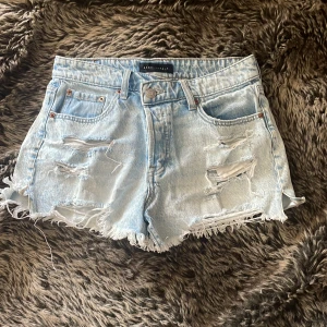Ljusa jeansshorts från Aeropostale - Säljer ett par ljusblå mom jeansshorts från Aeropostale med midwaist. Shortsen har slitna detaljer, fransig kant och klassisk femficksdesign. Materialet är jeans och de har en knapp och dragkedja framtill. Perfekta för sommarens chill dagar.