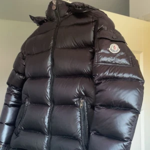 Svart Moncler pufferjacka med huva - Säljer Moncler Maya jacka herr som använts 1 vinter Storlek: 1 Scan logo funkar såklart Fick jackan i födelsedags present av min faster när hon va på Moncler butiken i Danmark.  På tredje bilden så kan ni se att den är lite skadad och just därför säljer jag den för så billigt. Standard pris på denna jackan är ungefär 10-12 tusen  