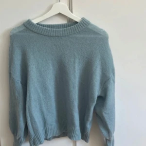 Ljusblå stickad tröja från MSCH - Supermysig ljusblå stickad tröja från MSCH Copenhagen i storlek XS/S. Tröjan har en rundad hals med ribbad kant och ribbade muddar vid ärmslut och nederkant. Perfekt för dig som gillar enkel och stilren design med soft vibe. Tröjan är aldrig använd.