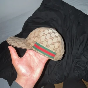 Gucci Keps Beige - Äkta beige Gucci keps i storlek M, säljer för att jag tröttnat på den ända defekten är att knoppen där uppe inte sitter kvar men det är inget som syns eller som påverkar kepsen men därav det låga priset, kan gå ner i pris vid snabb affär