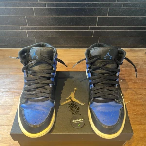 Nike Air Jordan 1 Mid Royal Blue - Nike Air Jordan 1 Mid i färgen Black/Hyper Royal-White. Klassisk high-top siluett med svart och blått skinn, svarta snören och vit sula. Ikonisk Jumpman-logga på plösen och Swoosh på sidan. Kommer med originalkartong och restocks-verifiering. Köpta för 2500 kr och säljer dom för 400 kr.