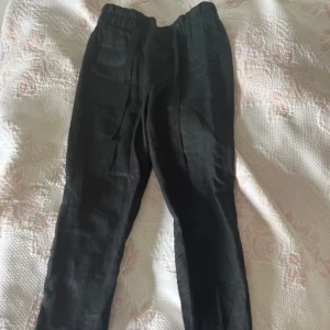 Svarta linnebyxor från Noa Noa - Svarta linnebyxor från Noa Noa med elastisk midja och dragsko. Byxorna har en avslappnad passform och är perfekta för en chill och stilren look. Materialet är svalt linne och de har en bakficka med knapp. Snygga och enkla att matcha till det mesta. Aldrig använda. 