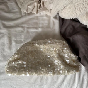 Vit paljettkuvertväska - Superfin kuvertväska i vit nyans, täckt med glittrande paljetter som ger en lyxig och trendig känsla. 