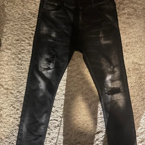 Svarta dondup jeans - Väldigt feta svarta jeans från Dondup med coola slitningar med lite washed/vitta kontraster runt låren och annat. Jeansen har en slim fit och är perfekt till hösten, dock har dom ett litet hål vilket du kan se på den sista bilden men detta är väldigt enkelt att lösa med bara en nål och en tråd.