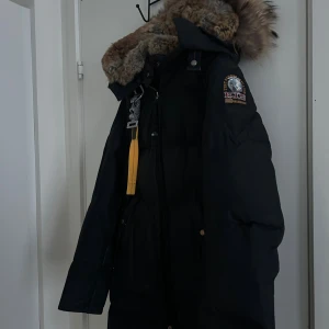 Parajumper long bear - Säljer en svart lång long bear från Parajumpers med stor pälskantad huva (gammal modellen som ej säljs mer med päls). Jackan har dragkedja, knappar och patch på ärmen. God skick. 