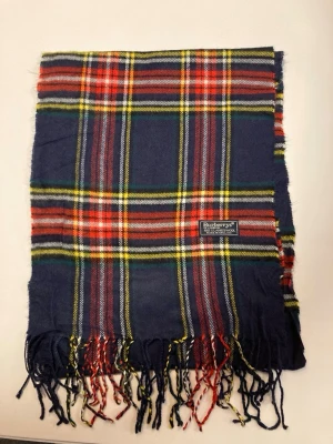 Rutig ullväst från Burberrys - Vi säljer denna otroligt snygga halsduk från Burberry med färgerna blå, gul, vit och röd utan defekter