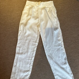 Vita linnebyxor från & Other Stories - Säljer ett par vita linnebyxor från & Other Stories med elastisk midja och snörning. Byxorna har avslappnad passform och raka ben, perfekta för varma dagar. Luftigt material och fickor i sidorna för en chill look.
