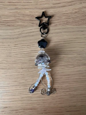 Svart manet-nyckelring med pärlor 🪼 🖤 - 🖤En manet som kan följa med på din resa! ⋅˚₊‧ ଳ⋆.ೃ࿔*:･  Maneten har glas komponenter så var försiktig! <3  Skriv i DM först, tack! ༊彡