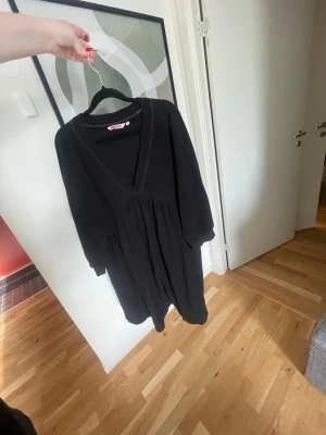 Svart klänning från Indiska - En svart klänning från Indiska i storlek M. Klänningen har v-ringning, långa ärmar och ett löst fall