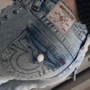 True Religion ljusblå bootcut jeans - Säljer ett par ljusblå jeans från True Religion i modell becca. Det är inprincip helt nya förutom att de saknas en knapp på ena fickan. Storlek 34