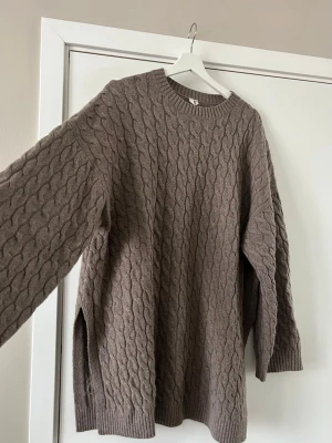 Brun kabelstickad ulltröja - Mysig brun kabelstickad tröja i 100% ull. Tröjan har rund halsringning, ribbade muddar och lång ärm. Är i storlek medium/large.