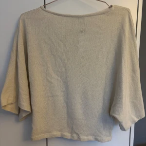 Beige stickad tröja med vida ärmar - Säljer en beige stickad tröja lösa ärmar som sitter tajtare kring midjan. Tröjan är stickad löst och kan upplevas som lite genomskinlig. Tröjan är oanvänd med prislappkvar.