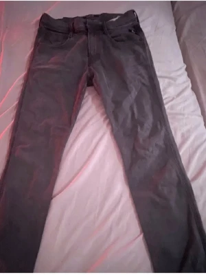 Replay svarta jeansbyxor herr 30/30 - Säljer ett par svarta Replay jeansbyxor i klassisk rak modell. Byxorna har fem fickor, bälteshällor och dragkedja. Materialet är slitstarkt jeans och färgen är mörk svart, vilket gör dem enkla att matcha med olika stilar.