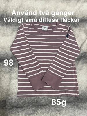 Randig långärmad t-shirt Polarn O. Pyret - Säljer en långärmad t-shirt från Polarn O. Pyret i lila och vitt med klassiska horisontella ränder. perfekt för chill dagar. Rund halsringning och breda muddar vid ärmslut. Enkel och stilren design.🌸 Använd två gånger. Väldigt små diffusa fläckar. Storlek 98