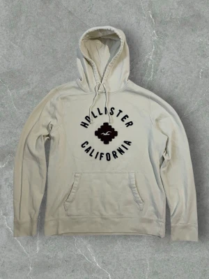 Hollister Beige Hoodie with Red Square Logo – Size L - Hollister beige hoodie featuring a red square logo on the front. Soft, comfortable and easy to style for everyday wear. Classic fit. Size Large. Great condition.  #hollister #hoodie #beigehoodie #streetwear #casualstyle #sizeL #vinted
