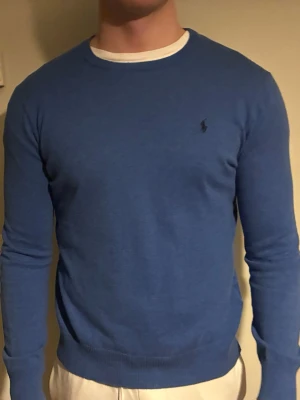 Blå tröja från Polo Ralph Lauren S - Säljer en klassisk blå tröja från Polo Ralph Lauren i  bomull. Tröjan har rund halsringning, diskret logga på bröstet och långa ärmar. Perfekt till jeans eller chinos. Storlek S felmärkt. Nypris 1500