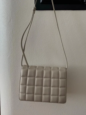 Beige väska från H&M - Superfin och användbar grå/beige väska från H&M. Är väldigt rymlig trots att den inte alls upplevs som stor. 🌸 Använd fåtal gånger, i fint skick. Har ett litet märke som knappt syns på nära håll (se närbilden).  Nypris ca 300 kr.