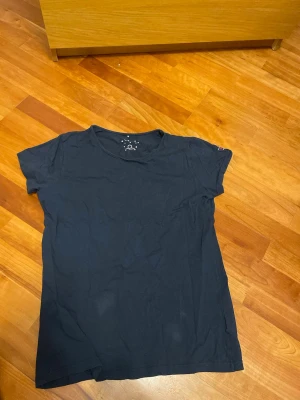 Mörkblå t-shirt från Polarn O. Pyret - Enkel och stilren mörkblå t-shirt från Polarn O. Pyret. Klassisk rund halsringning och korta ärmar. Tillverkad i mjuk bomull som känns skön mot huden. Liten logga på ärmen för en clean look.