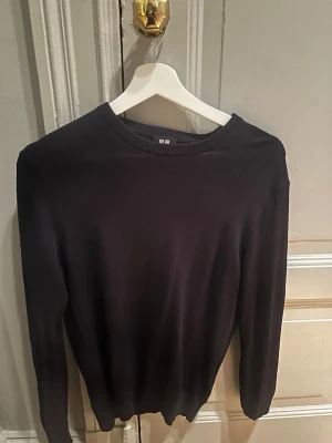 Svart stickad tröja från Uniqlo - En stilren svart stickad tröja från Uniqlo i storlek S. Tröjan har rund halsringning och långa ärmar, perfekt för lager på lager under kyligare dagar. Enkel och klassisk design som funkar till det mesta.