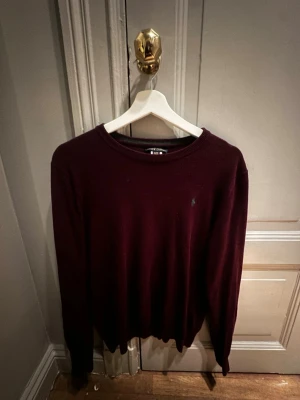 Vinröd tröja från Polo Ralph Lauren - Säljer en vinröd långärmad tröja från Polo Ralph Lauren. Klassisk rund halsringning och diskret broderad logga på bröstet. Tröjan är i mjukt material och passar perfekt till kyligare dagar.