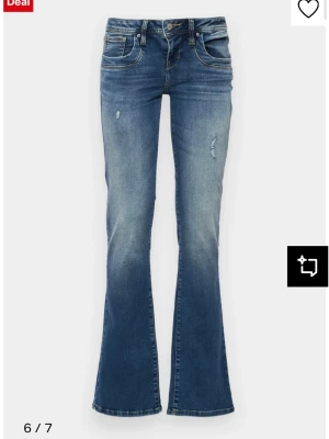 Blå bootcut jeans från LTB, 26/32 - Säljer ett par blå bootcut jeans från LTB i storlek 26/32. Jeansen har låg midja, slitna detaljer framtill och klassisk femficksmodell. Materialet är jeans med en snygg tvättad look och lätt utsvängda ben. Perfekta för dig som gillar retrovibbar och bekväm passform.
