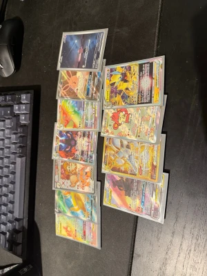 Samling Pokémonkort GX/V/VMAX - Stor samling Pokémonkort med massor av GX, V och VMAX-kort. Flera kort har färgglada och glittriga motiv, vissa med guld- och regnbågseffekter. Perfekt för dig som vill boosta din samling med coola och sällsynta kort. Alla kort är i plastfickor.