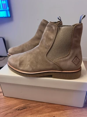 Beige chelsea boots i mocka från Gant - Säljer ett par snygga beige chelsea boots från Gant i mjuk mocka. Skorna har elastiska matrixpaneler på s com sidorna food enkel påtagning och en klassisk guard sula. Perfekta till både jeans och chinos för en clean look.