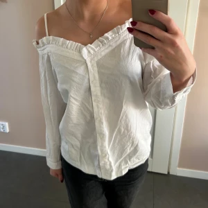 Vit offshoulder skjorta med volang - Säljer denna vita offsholder skjorta/blus då den inte kommer till användning längre. Väldigt bra skick, använd fåtal gånger! Skriv vid fler bilder/frågor!🥰