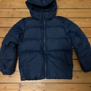Pufferjacka från Tommy Hilfiger - Säljer denna snygga och varma Tommy Hilfiger jackan. Den är perfekt nu när det börjar bli lite kallare väder utomhus. Den är i mycket bra skick. Hör av er om ni har några funderingar