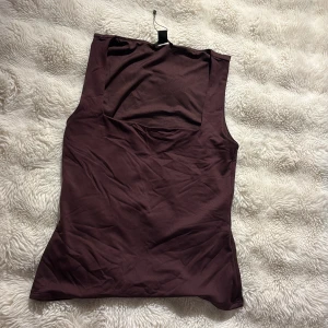 Vinröd ärmlös linnetopp från newyorker - Snygg vinröd linnetopp från newyorker med fyrkantig halsringning och ärmlös design. Toppen är gjord i mjuk bomull och har en slim passform som sitter skönt mot kroppen. Perfekt att styla med jeans eller kjol för en clean look.