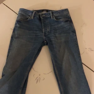 Blå jeans från Neuw Stockholm - Snygga blå jeans från Neuw Stockholm med klassisk femficksdesign och ljusare tvättade detaljer. Jeansen har rak passform och normal midja, tillverkade i slitstarkt bomullsjeansmaterial. Perfekt för dig som gillar stilrena och tidlösa jeans.