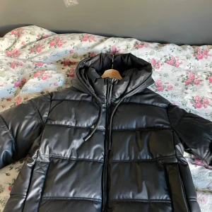 Svart pufferjacka från Zara - Säljer en svart pufferjacka från Zara. Materialet är syntet med en skinnliknande finish. Jag har använt den få tal gånger, den har inga skador eller fläckar❤️Den är även väldigt varm och en perfekt vinter jacka!