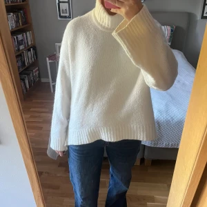 Vit polotröja från Samsøe Samsøe - Mysig vit polotröja från Samsøe Samsøe med oversized passform och breda, ribbade muddar. Tröjan är stickad och har en hög krage som ger extra värme. Perfekt för kyliga dagar och enkel att styla med jeans eller kjol.