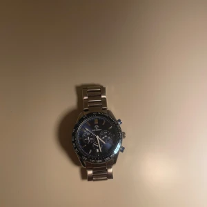 Blå kronografklocka från ADCASDIY - ADCASDIY herrklocka med blå urtavla och silverfärgat armband i metall. Klockan har kronograf-funktion, tachymeter på ringen och flera subdials. Snygga blå detaljer på knapparna och robust länkarmband. Perfekt för dig som gillar sportig och modern stil, använd max 5-6 gånger och säljer så biligt för jag inte har nån användning av den och vill bli av med den skriv privat så kan priset diskuteras