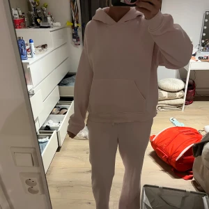 Ljusrosa mjuckis set från Gina Tricot XS - Mjukt och skönt ljusrosa mjuckis set från Gina Tricot, Basically Basics-kollektionen. Tröjan har huva, stor magficka och långa ärmar med ribbade muddar. Byxorna är ganska lågmidjade och super sköna Perfekt för chill dagar och har en loose passform som ger en avslappnad vibe. 💗