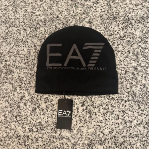 Emporio Aramani mössa - Säljer en helt ny svart EA7 mössa då jag fick den i present men inte använt den. Ny pris är runt 500kr men jag vill bara bli av med den