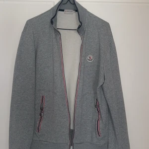 Moncler Ziptröja - Moncler tröja storlek M, står XL men sitter som en M. En liten annorlunda modell mot hur de brukar se ut men kollat runt mycket och fått den legit checkad och den är äkta, däremot i ett sämre skick.